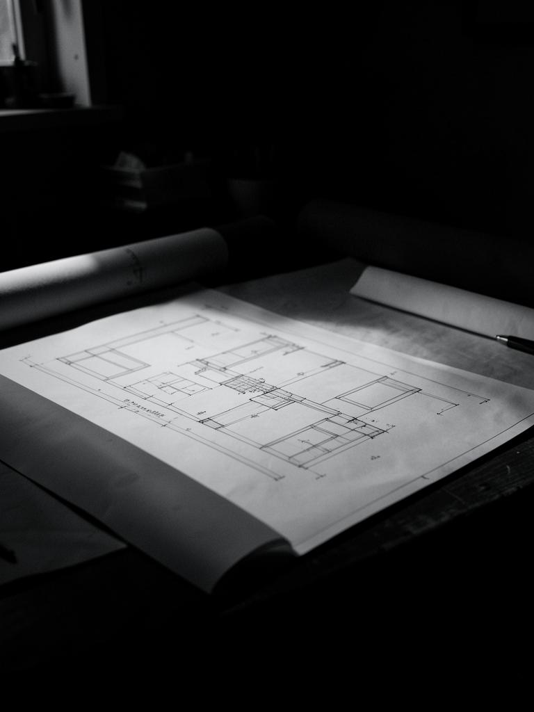 Architectural drawing set laid out on a drafting table in low light